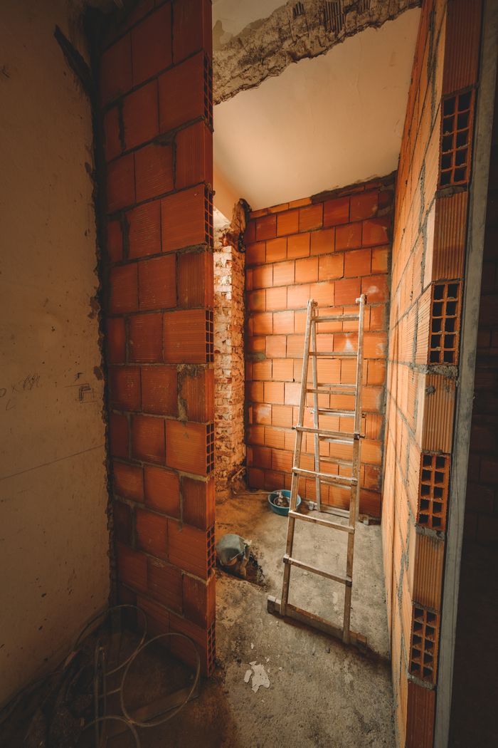 heros-img A construction site with a ladder leaning against red brick walls, showcasing renovation activities.