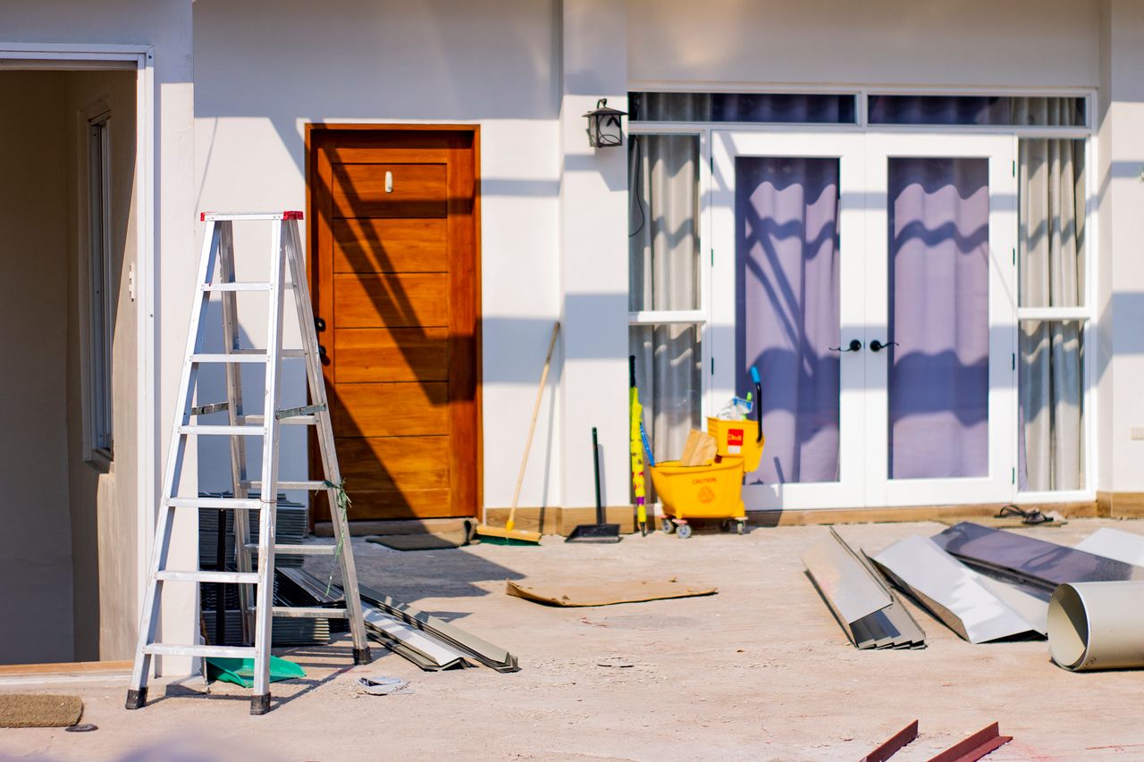 our-story Front entrance of a house under renovation with tools and materials scattered around.