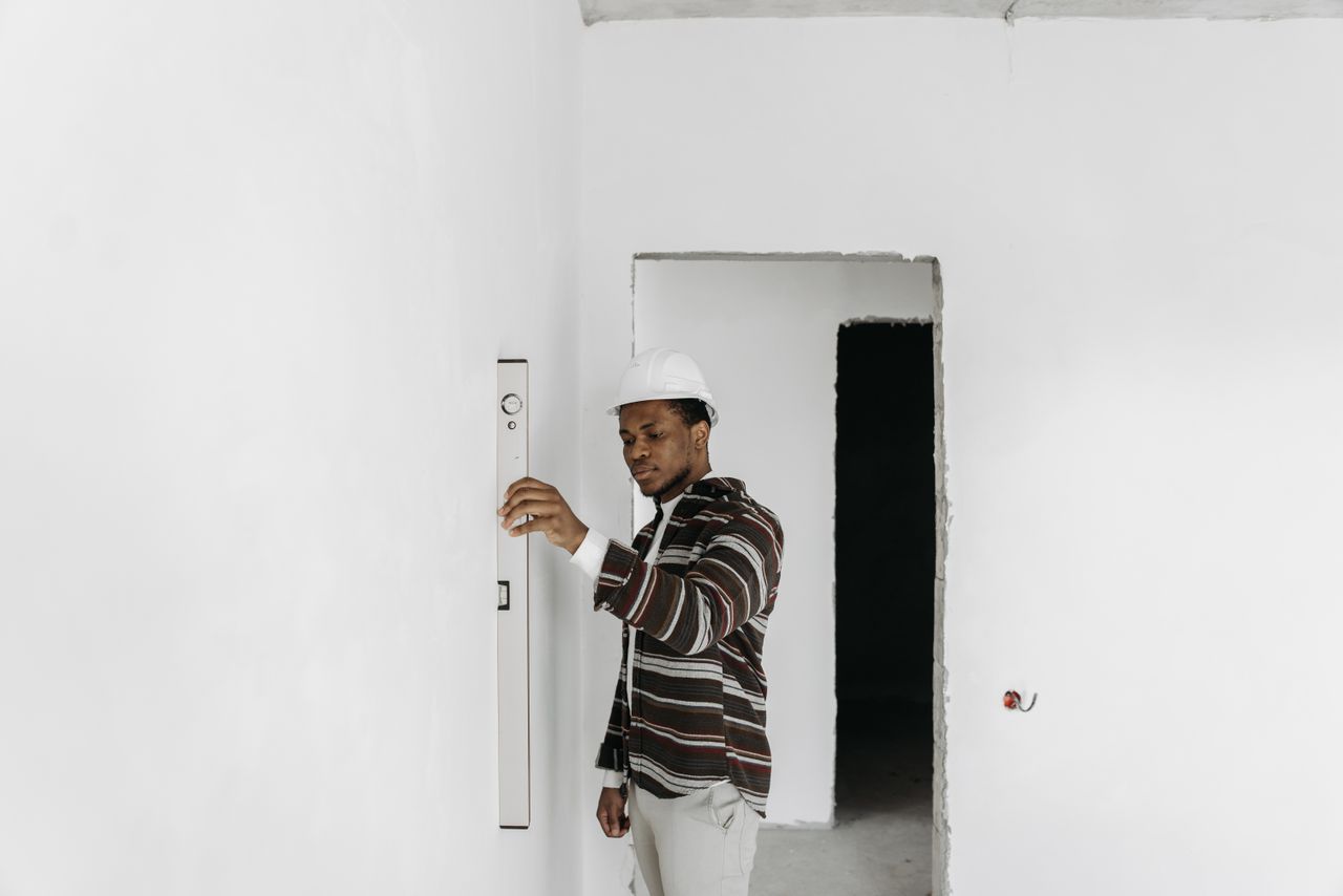 services-02 Architect wearing hard hat checks wall alignment in a renovation project.